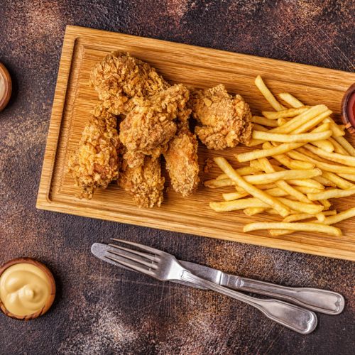 Fried chicken wings with french fries, top view.